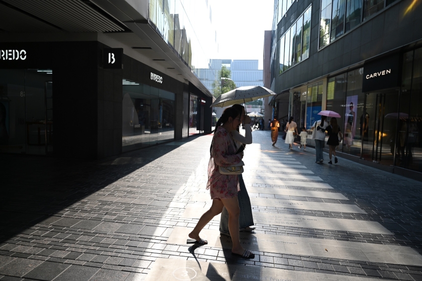 Seorang wanita menyeberangi jalan kota di tengah suhu yang panas