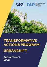 Sampul depan Program Aksi Transformatif UrbanShift Laporan Tahunan 2022. Foto bangunan dengan pepohonan di bagian depan dibatasi oleh blok-blok berwarna kuning, biru, dan hijau pucat.